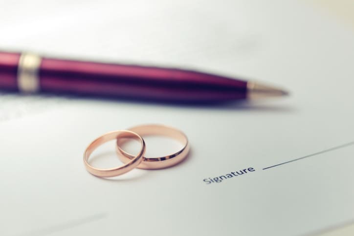caneta e duas alianças em cima de uma certidão de casamento após passar por uma tradução juramentada