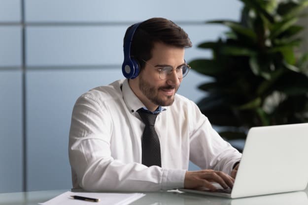 Tradução juramentada online Homem sentado em mesa de escritório, mexendo em tradução juramentada online.