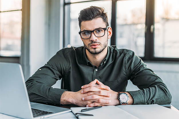 motivos da importância da contratação de uma empresa de tradução Homem em um escritório trabalhando em uma empresa de tradução em seu notebook
