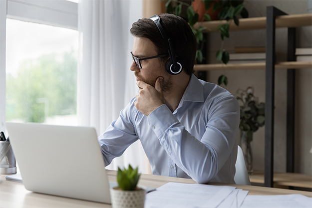 tradutor sentado em seu ambiente de trabalho com fones de ouvido e uma janela ao lado