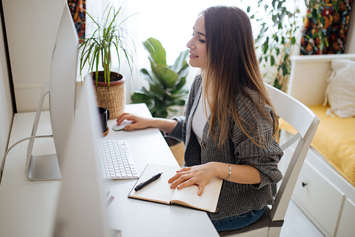 Mulher em frente ao computador verificando documentos estrangeiros que exigem tradução juramentada.