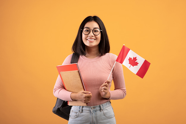 mulher de cabelos escuros pronta para fazer um intercâmbio voluntário com a bandeira do Canadá na mão.