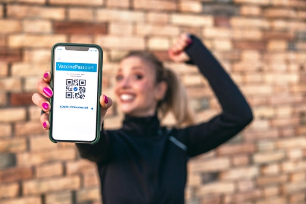 saiba quando é recomendada a tradução jjuramentada do certificado de vacinação internacional. mulher segurando na mão o seu passaporte de vacinação internacional após processo de tradução juramentada