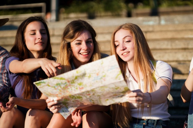 meninas planejando um intercâmbio barato enquanto olham um mapa global