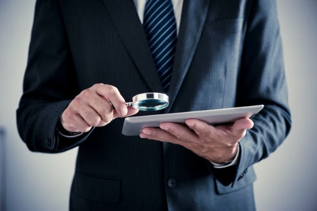 homem analisando com lupa documentos