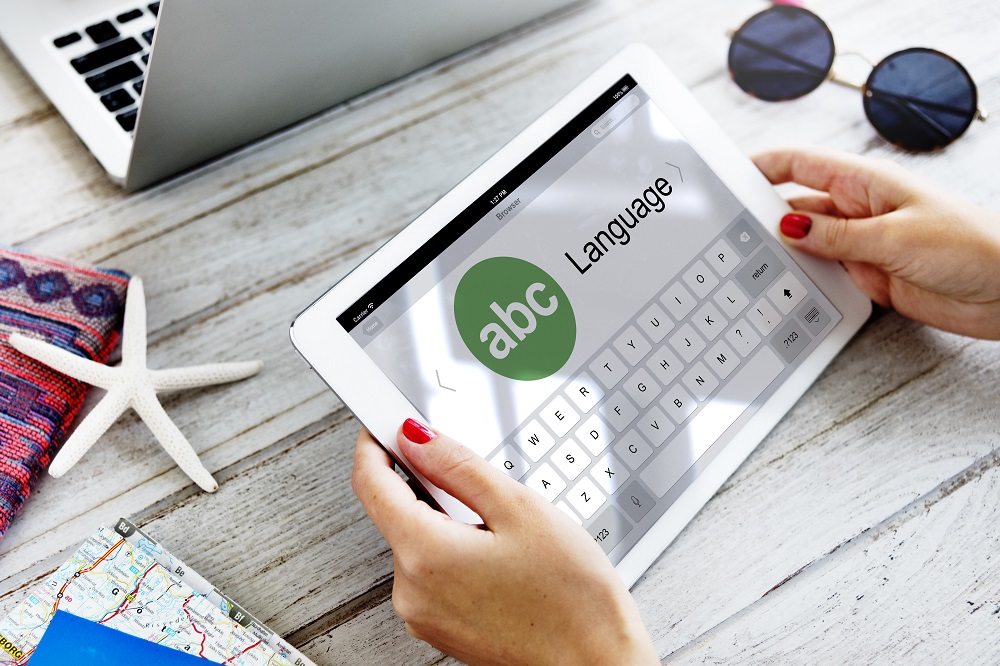 Pessoa com um tablet na mão buscando por uma agência de tradução.