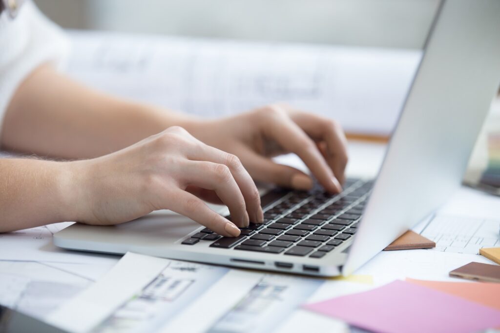 mãos de um tradutor apoiada no teclado do notebook e traduzindo um documento do inglês para o português