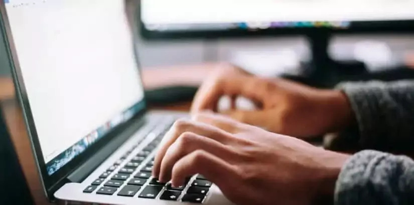 mãos digitando em um notebook realizando tradução juramentada de diploma